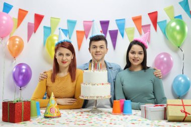 Gençler parti şapkaları ve süslemeleri ile bir duvara bir doğum günü pastası ile