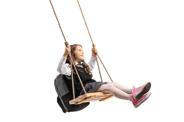 Little schoolgirl swinging on a wooden swing isolated on white background