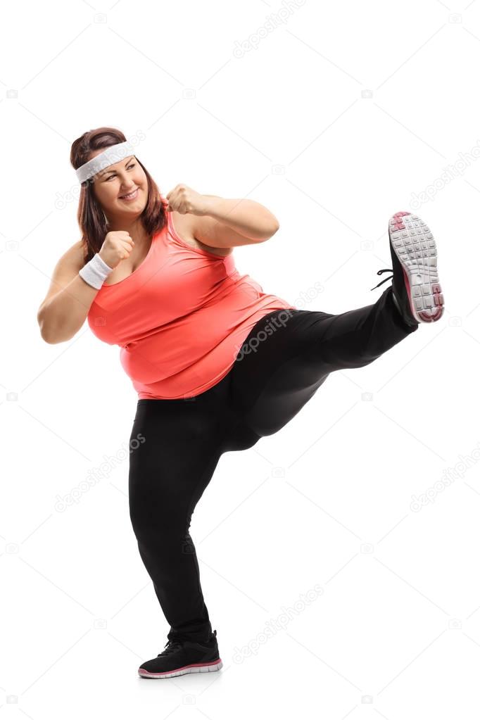 Full length portrait of an overweight woman kicking isolated on white background