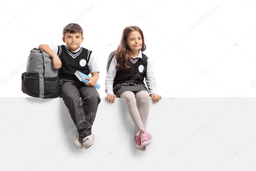 Schoolboy and a schoolgirl sitting on a panel isolated on white background