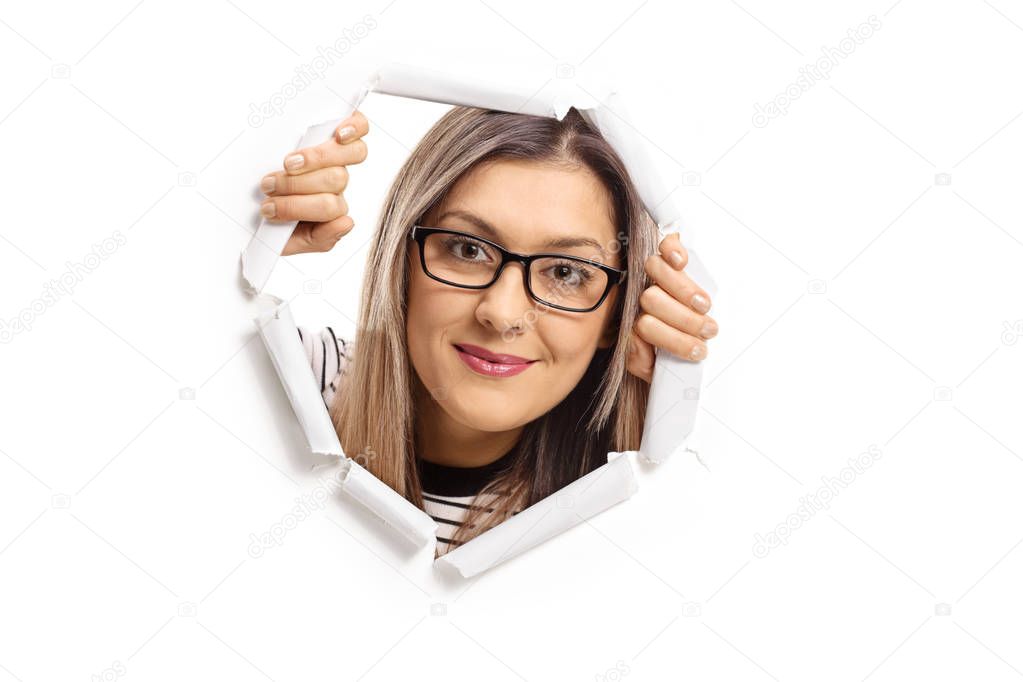 Young woman peeping through a paper hole isolated on white background