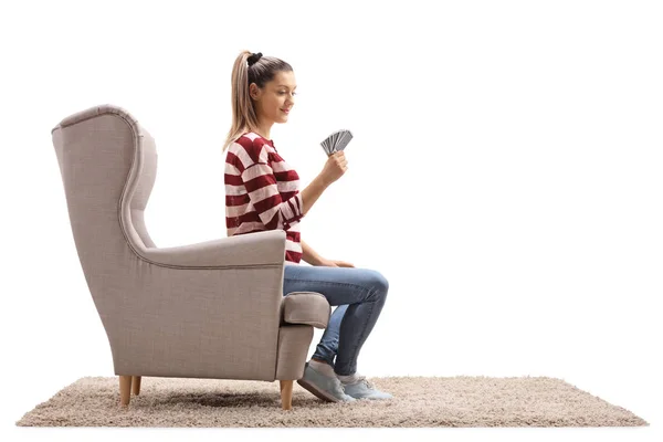 白い背景に分離された肘掛け椅子に座ってトランプを持つ若い女性 — ストック写真