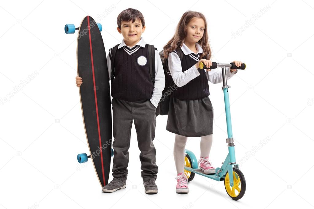 Full length portrait of a schoolboy with a longboard and a schoolgirl with a scooter isolated on white background