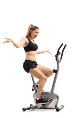 Beyaz arka plan üzerinde izole bir çapraz-eğitmen makinede egzersiz memnun bir genç kadının tam uzunlukta profil vurdu