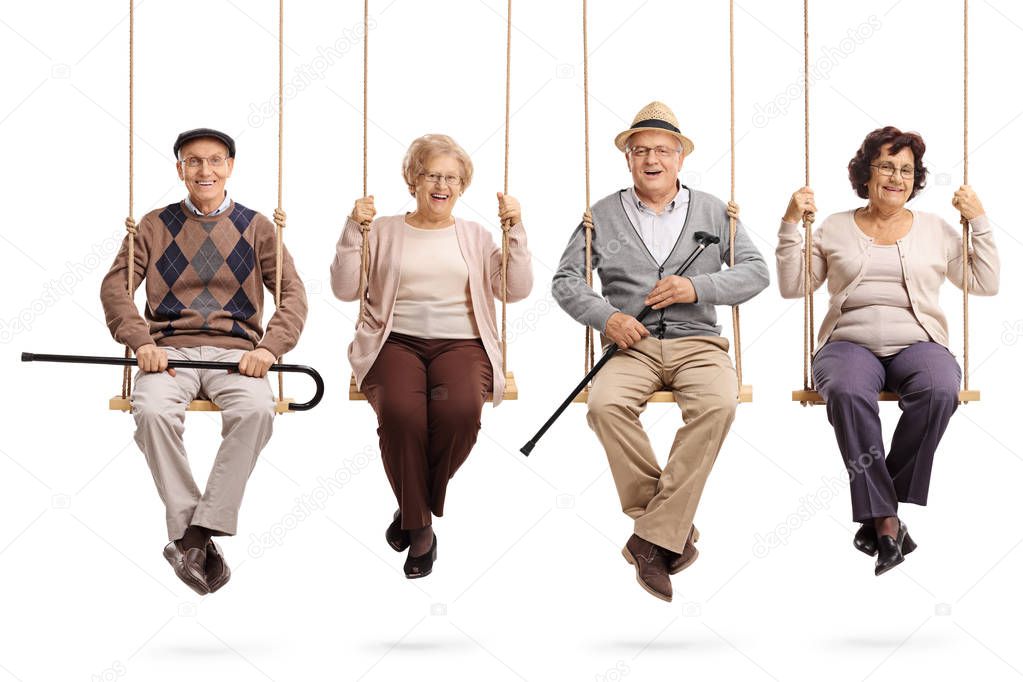 Cheerful seniors sitting on wooden swings and looking at the camera isolated on white background
