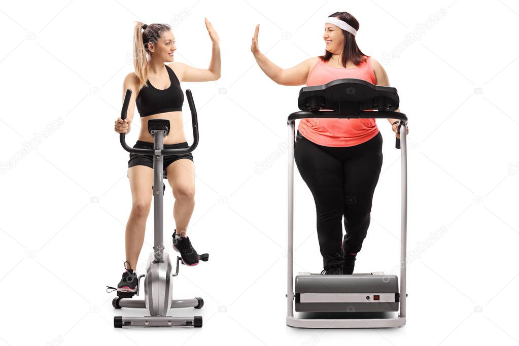 Full length profile shot of two young women exercising and high-fiving each other isolated on white background