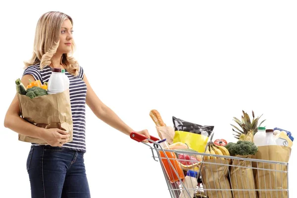 紙の袋や白い背景で隔離の食料品でいっぱい買い物カゴを持つ若い女性 — ストック写真