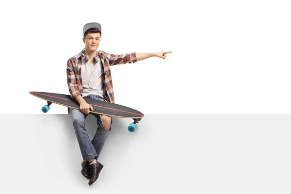 Skater Remaja Dengan Papan Panjang Duduk Panel Dan Menunjuk Terisolasi — Stok Foto
