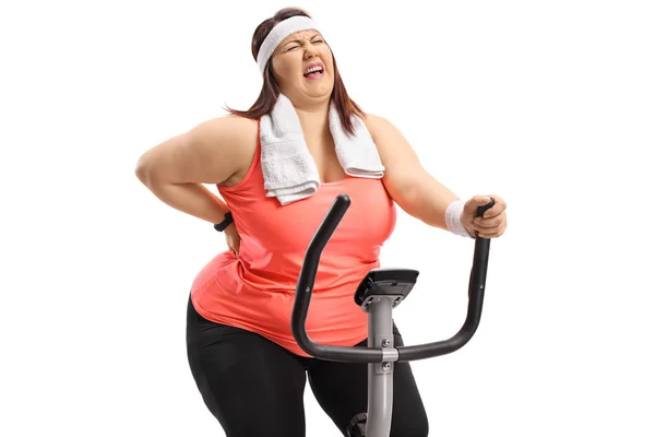 Overweight Woman Riding Exercise Bike Experiencing Back Pain Isolated White — Stock Photo, Image