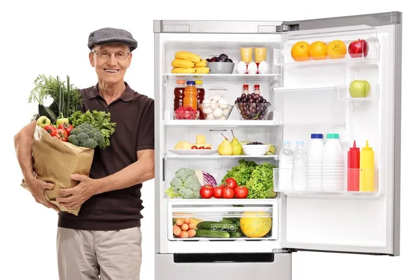 Senior Mit Einer Tüte Lebensmittel Lehnt Einem Kühlschrank Isoliert Auf — Stockfoto