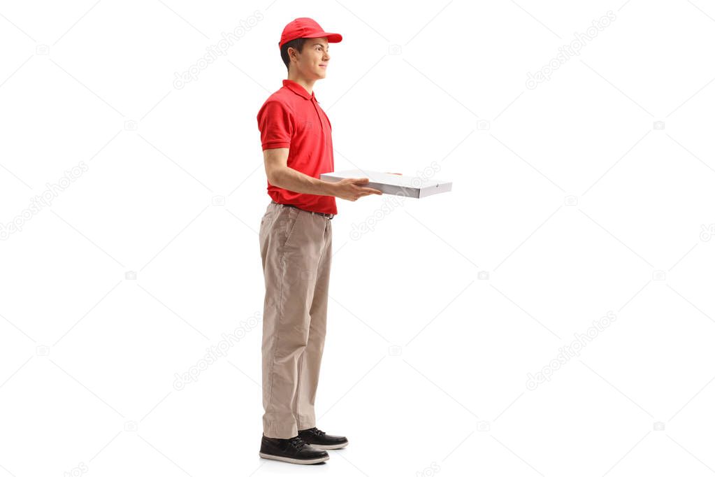 Full length profile shot of a teenage delivery boy holding a pizza box isolated on white background