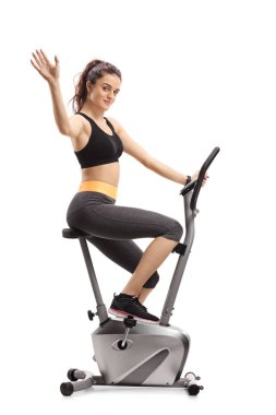Bir egzersiz bisikleti çalışma dışarı ve beyaz arka plan üzerinde izole kamera sallayarak fitness kadın