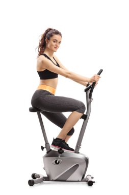 Bir egzersiz bisikleti binme ve beyaz arka plan üzerinde izole kamera bakarak fitness kadın