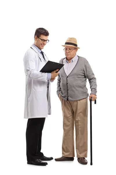 医者と白い背景に分離されたクリップボードを見て高齢者患者の完全な長さの肖像画 — ストック写真