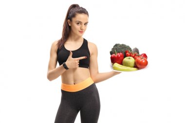 Fitness kadın beyaz zemin üzerine bir tabak sebze ve meyve tutan ve işaret izole