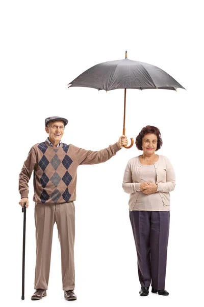 白い背景上に孤立高齢者女性に傘を保持している年配の紳士の完全な長さの肖像画 — ストック写真