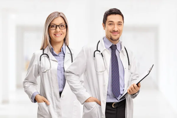 Female doctor and a male doctor with a clipboard looking at the camera and smiling