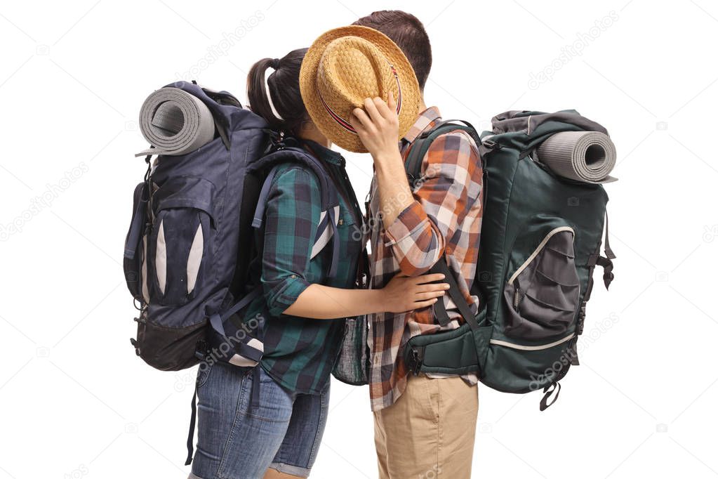 Teenage tourists kissing and hiding behind a hat isolated on white background