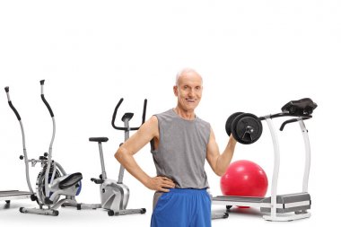 Beyaz arka plan üzerinde izole egzersiz makineleri önünde bir dumbbell ile yaşlı adam