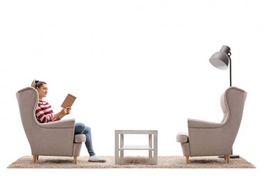 Bir koltukta oturan ve beyaz arka plan üzerinde izole bir kitap okuma kadın