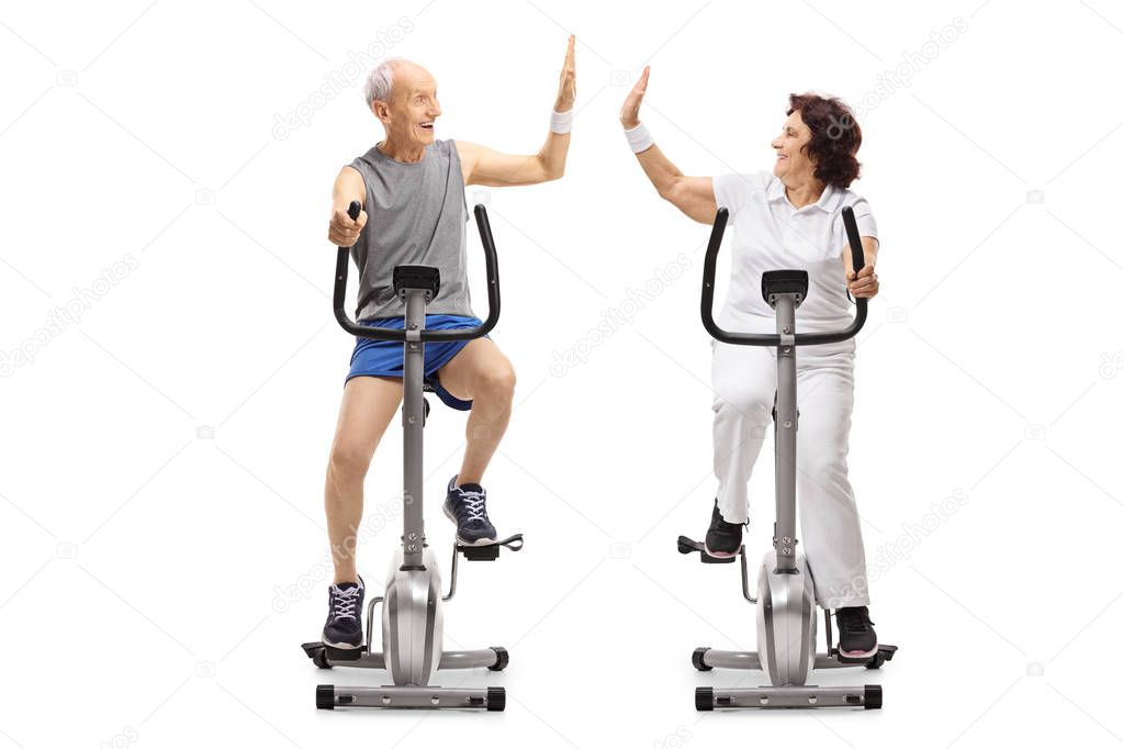 Seniors on exercise bikes high-fiving each other isolated on white background
