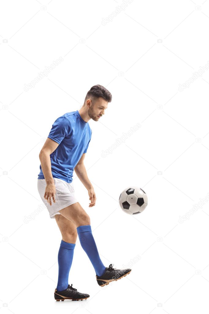 Full length profile shot of a soccer player with a football isolated on white background