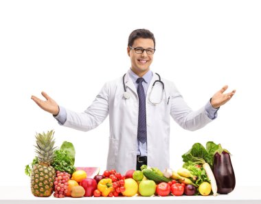 Doktor meyve ve sebze elleriyle beyaz arka plan üzerinde izole el hareketi ile bir masanın arkasında