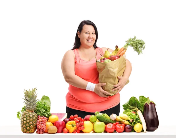 太りすぎの女性の果物や野菜は 白い背景で隔離のテーブルの後ろの食料品袋 — ストック写真