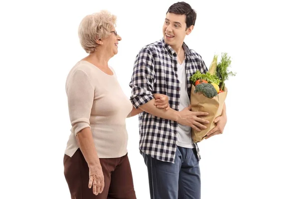 年轻男子帮助一个老太太与她的杂货被隔离在白色背景 — 图库照片