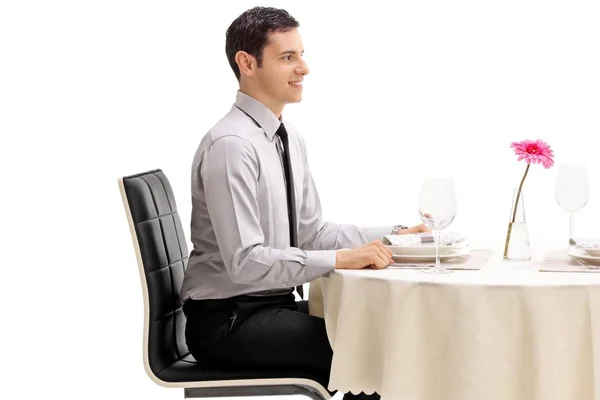年轻男子坐在餐厅餐桌上 在白色背景隔离 — 图库照片