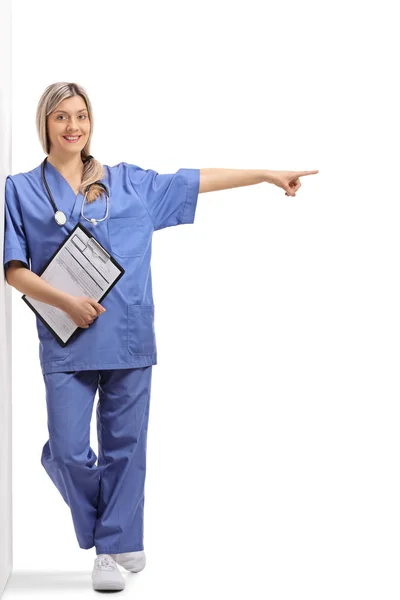 Full Length Portrait Female Doctor Clipboard Leaning Wall Pointing Isolated — Stock Photo, Image