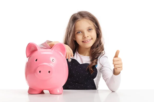 Little Girl Piggybank Sitting Table Making Thumb Gesture Isolated White — Stock Photo, Image