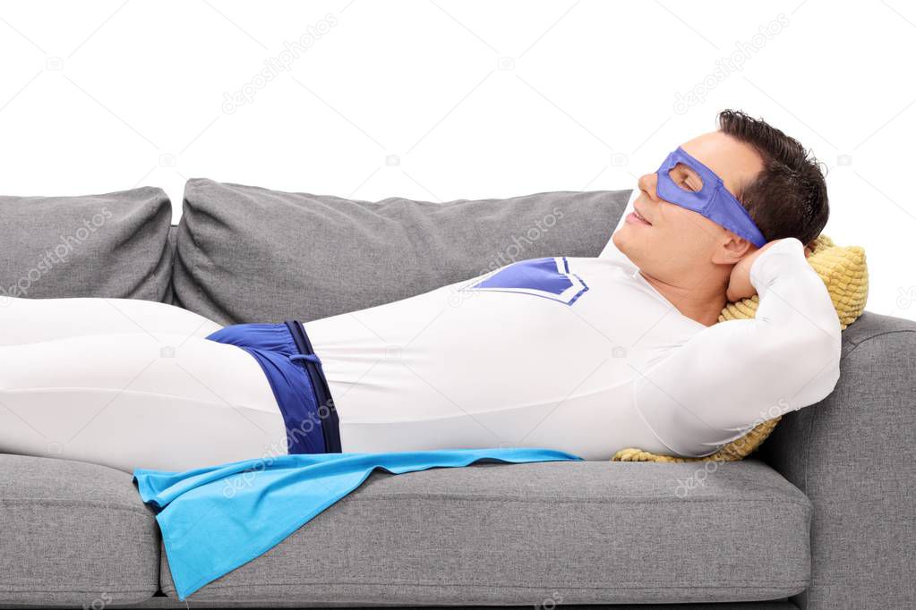 Man in a superhero costume sleeping on a couch isolated on white background