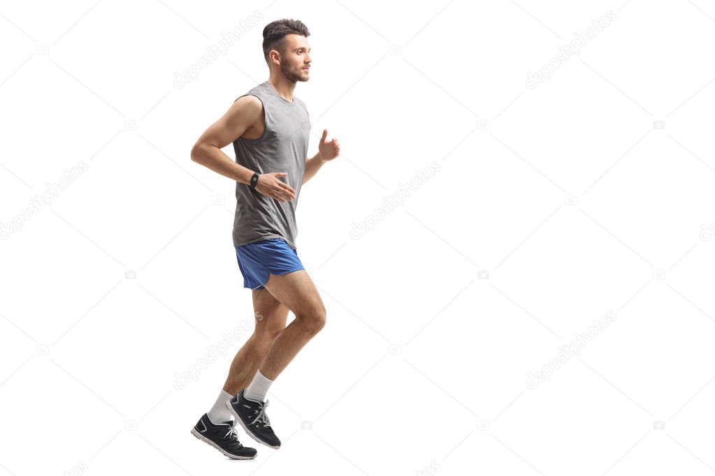 Full length profile shot of a young man in sportswear running isolated on white background
