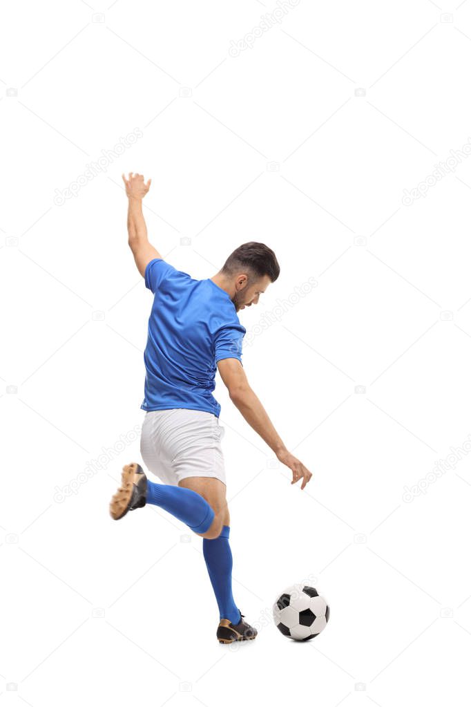 Full length rear view shot of a soccer player kicking a football isolated on white background