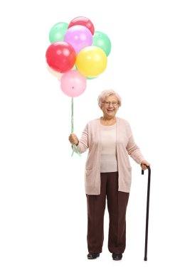 Tam uzunlukta bir sürü balonlar ve beyaz arka plan üzerinde izole bir baston tutan bir neşeli yaşlı kadın portresi