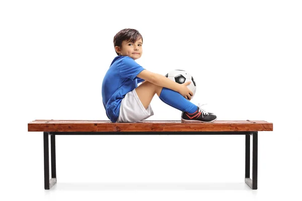 Weinig Voetballer Een Houten Bankje Zitten Kijken Naar Camera Geïsoleerd — Stockfoto