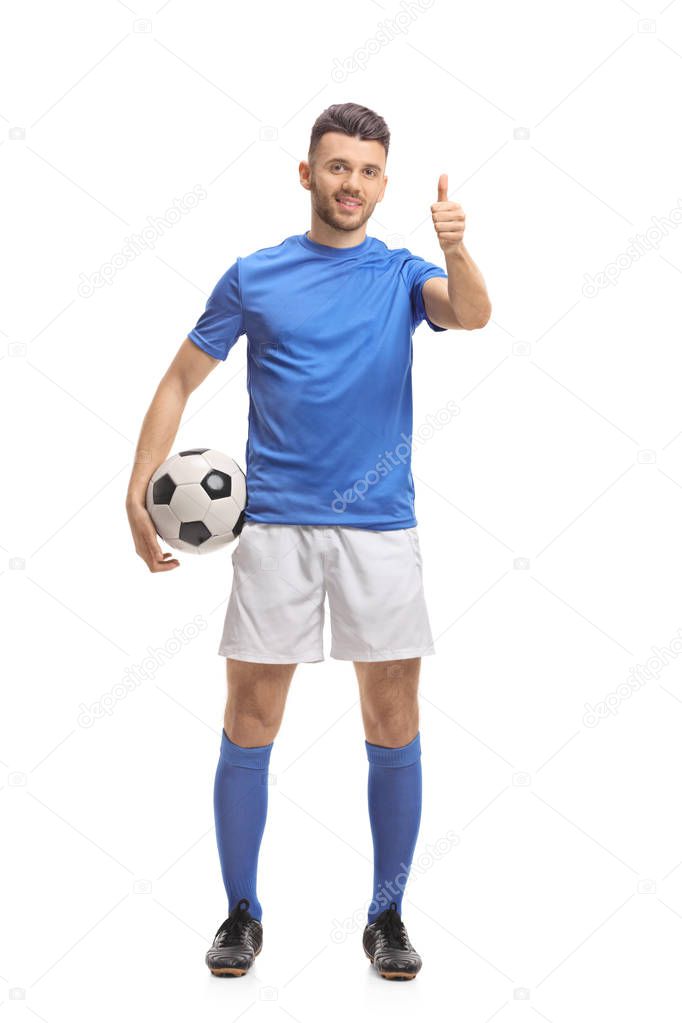 Full length portrait of a soccer player holding a football and making a thumb up sign isolated on white background