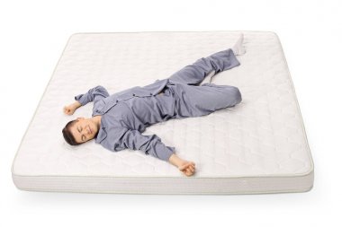 Beyaz arka plan üzerinde izole bir yatak üzerinde uyuyan genç çocuk