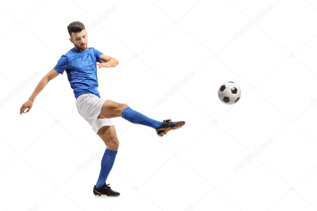 Full length portrait of a soccer player kicking a football isolated on white background