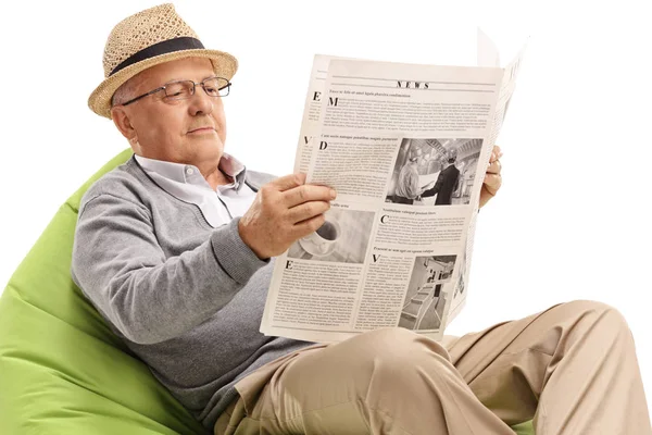 Sénior Sentado Saco Feijão Lendo Jornal Isolado Fundo Branco — Fotografia de Stock