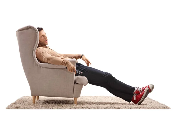 白い背景に分離された肘掛け椅子で眠っているリモコンで若い男 — ストック写真