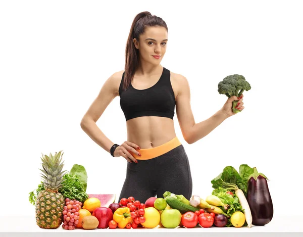健身妇女在桌子后面的水果和蔬菜在白色背景下保存花椰菜 — 图库照片