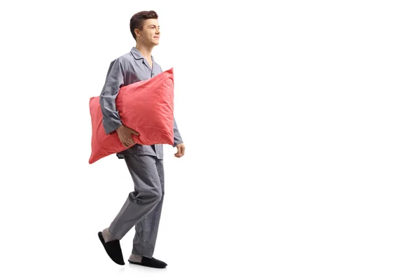 一个十几岁的男孩穿着睡衣的全长剖面照片抱着一个枕头 走在白色背景上独立行走 — 图库照片