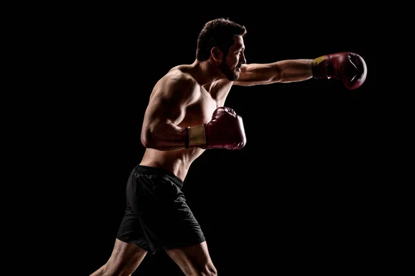 Δυνατός μυώδης άνδρας με γάντια πυγμαχίας ρίχνει μια γροθιά — Φωτογραφία Αρχείου