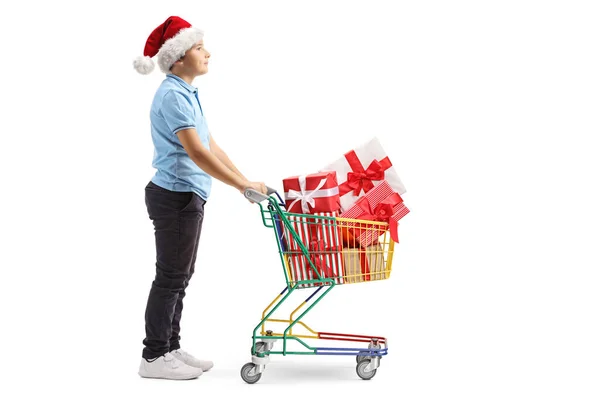 Ragazzo con un cappello di Babbo Natale spingendo un mini carrello della spesa con pre — Foto Stock