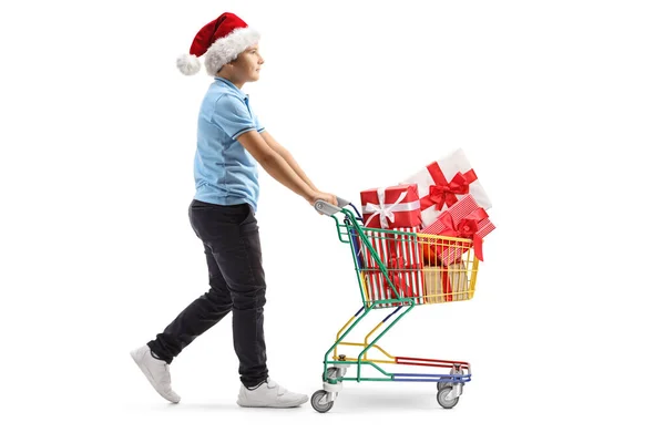 Garçon avec un chapeau de Père Noël poussant un chariot avec des cadeaux — Photo