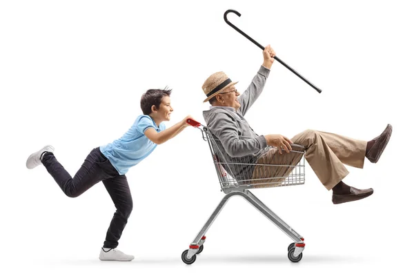 Menino empurrando seu avô louco em um carrinho de compras — Fotografia de Stock