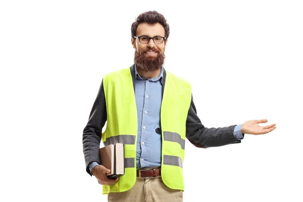 Homem segurando livros, vestindo colete de segurança e gesticulando sagacidade bem-vinda — Fotografia de Stock