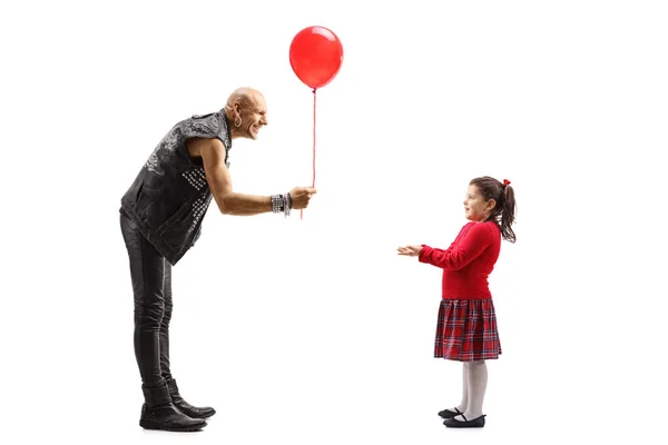 Erkek rock yıldızı küçük bir kıza kırmızı balon veriyor. — Stok fotoğraf